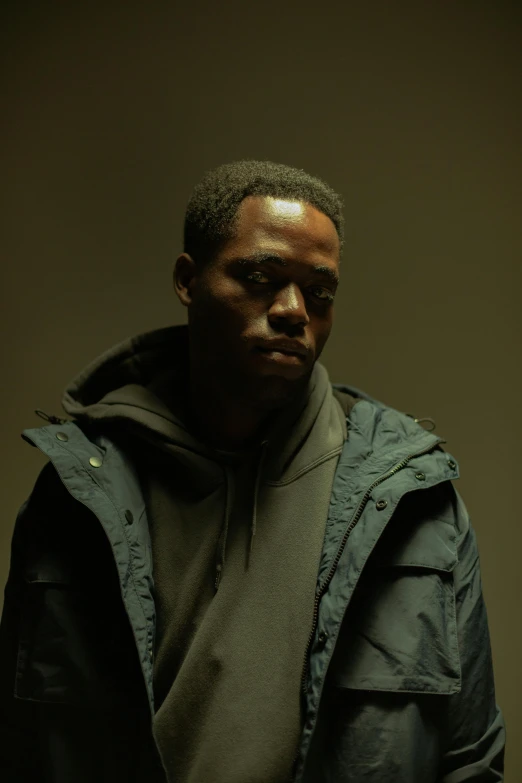 a black man with a green hoodie looking directly into the camera