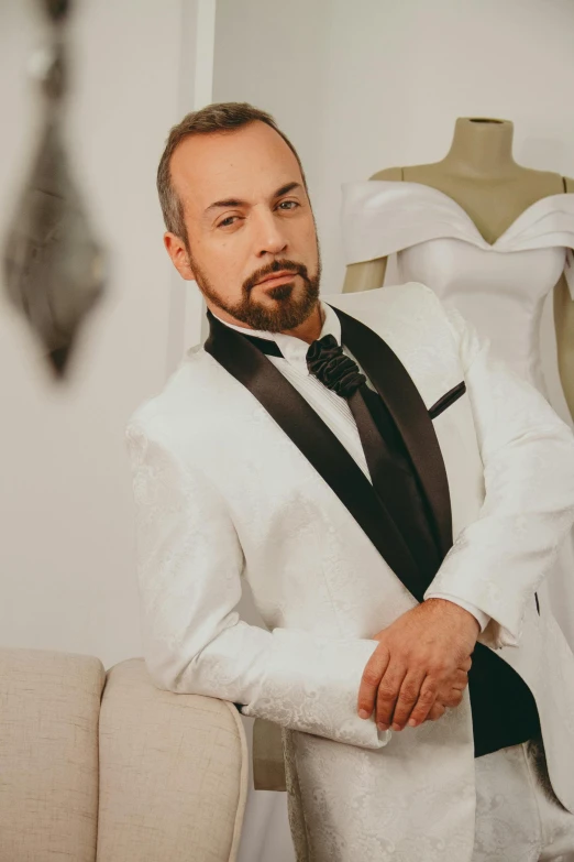 man wearing white suit and black tie, looking intently at his back