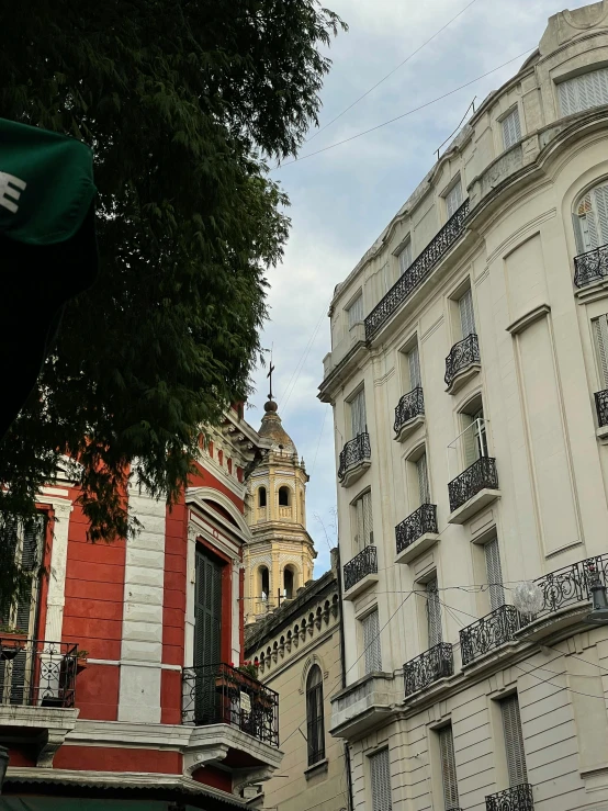 a building with two balconies on the second story and the third floor above it is another building and has a green umbrella over it