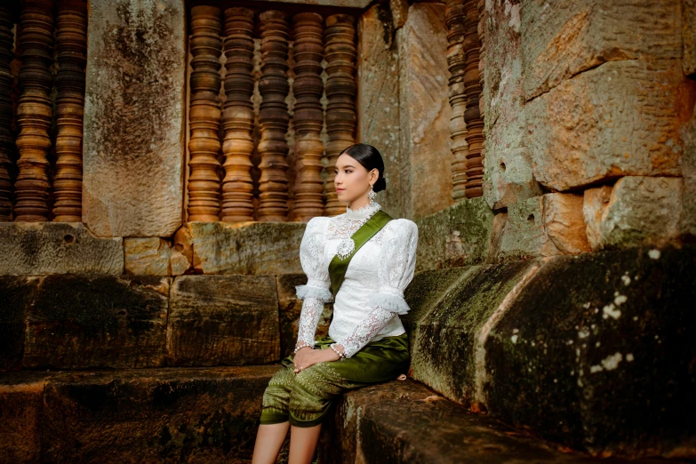 a woman is wearing green shorts and sitting on stone
