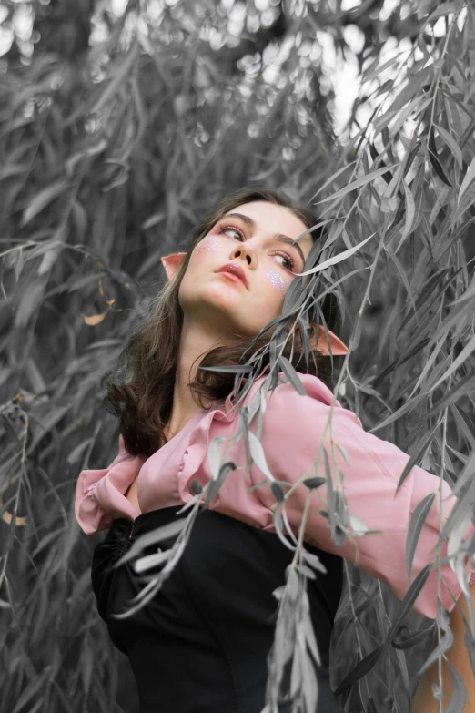 a woman in pink shirt hiding her face behind some nches