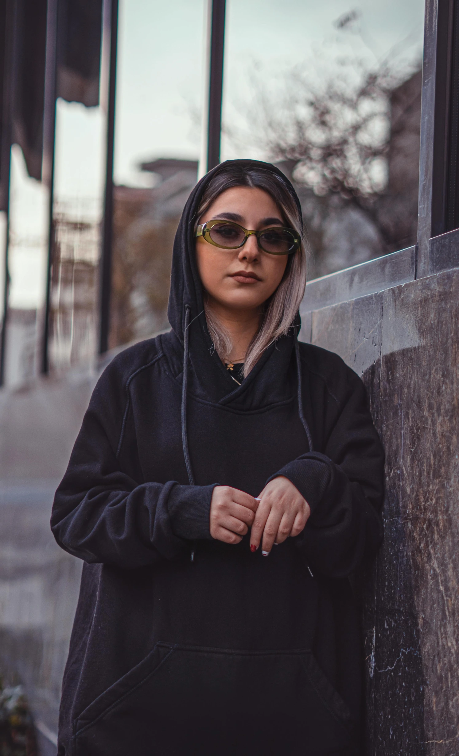 a woman wearing sunglasses posing next to a building