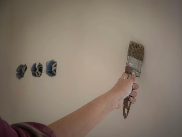 a person holding a paint brush by some wall art