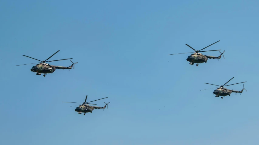 four military helicopter are flying close to each other