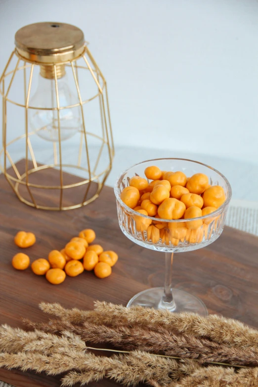 oranges sitting in a glass dish on a wooden table