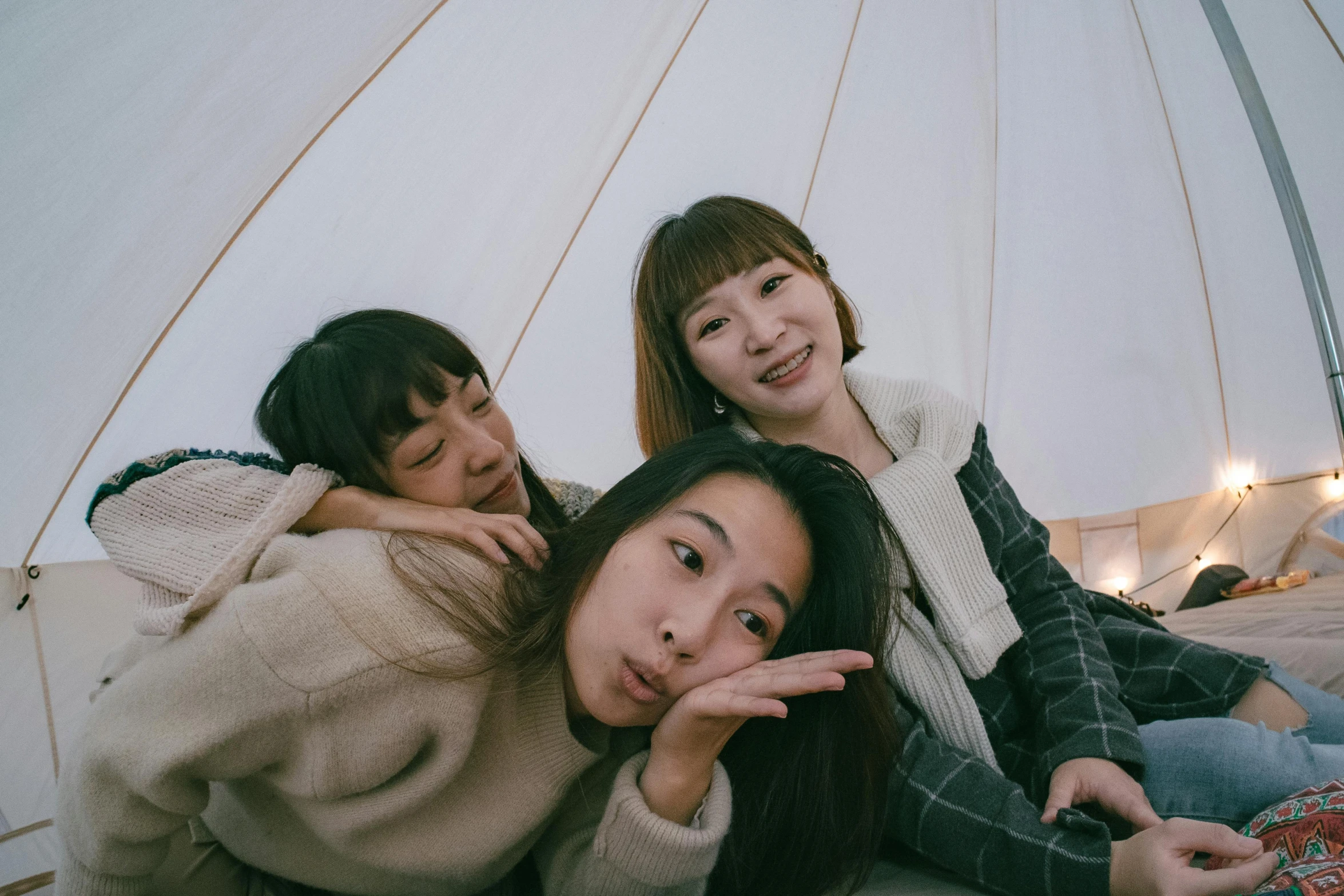 four s sitting outside in a tent, smiling