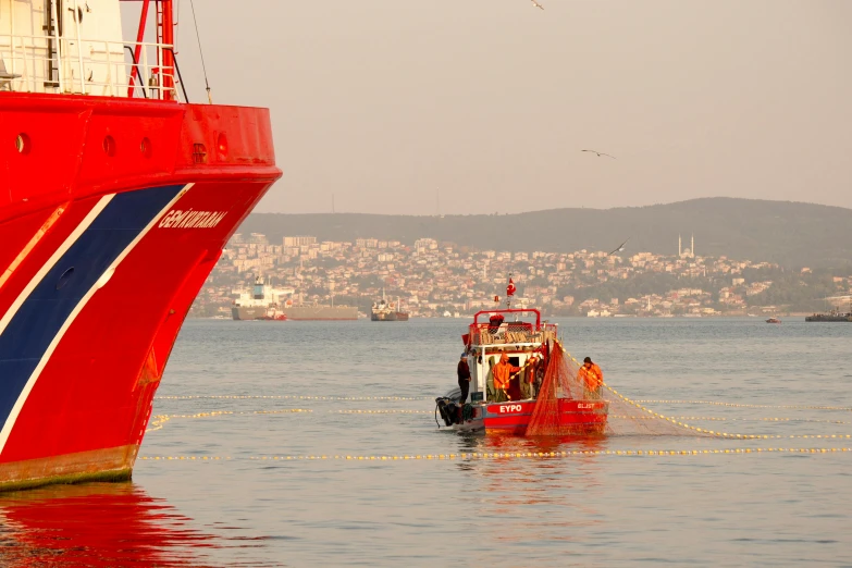 a red tug boat with a tug boat behind it