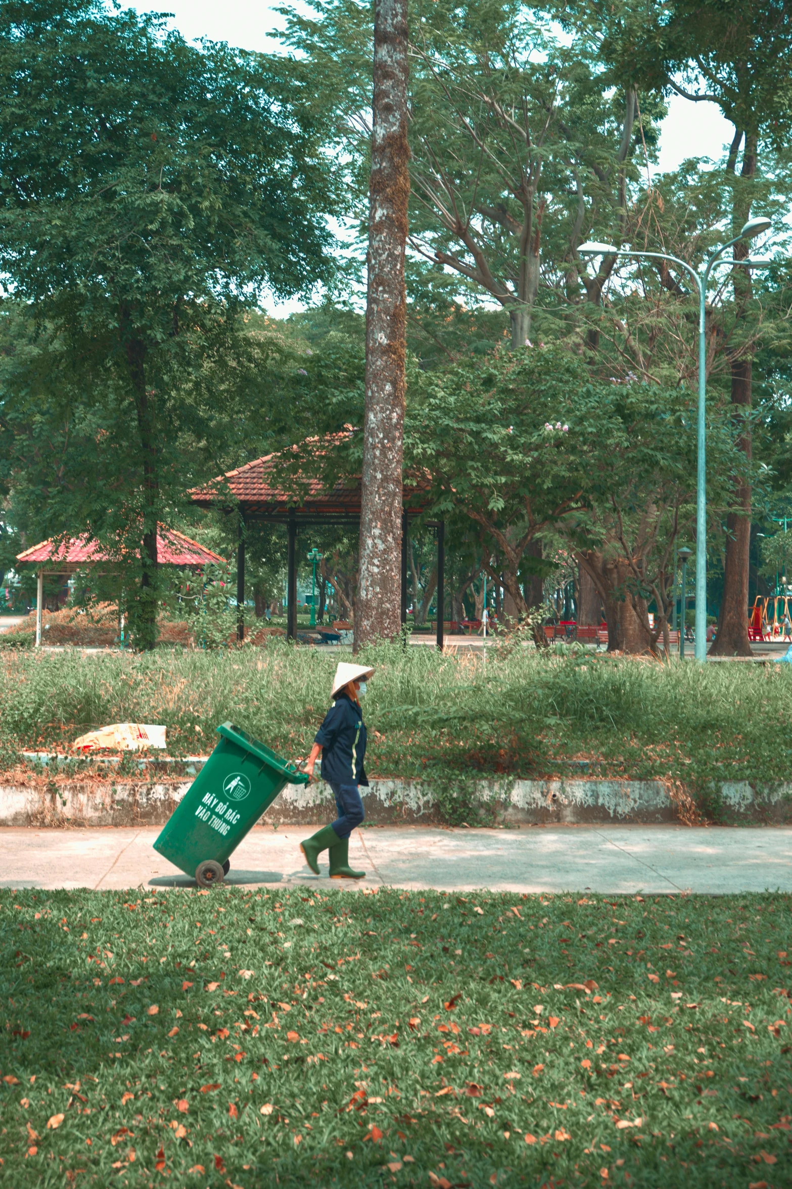 person walking with a green bin and red umbrella