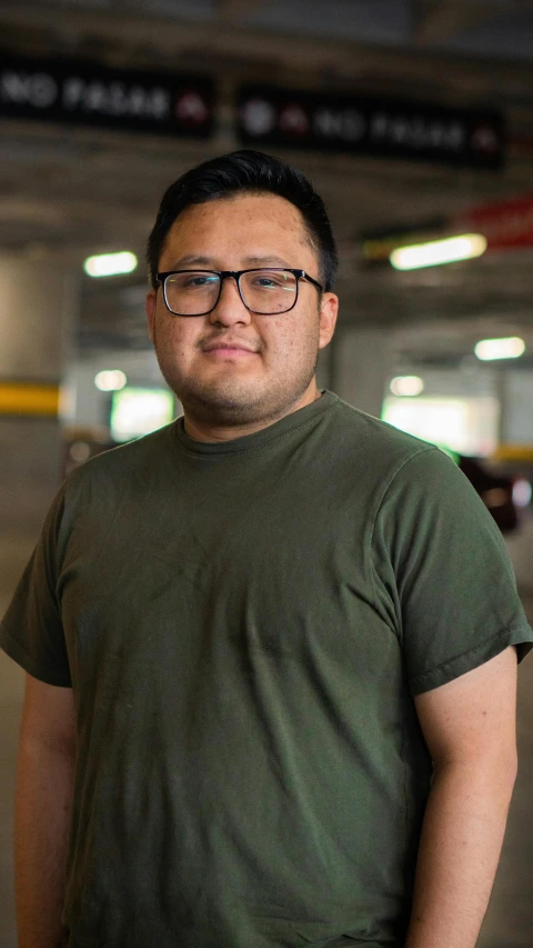 a male in glasses and a brown shirt