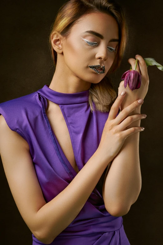 a woman with makeup on her face and a purple dress holding a flower