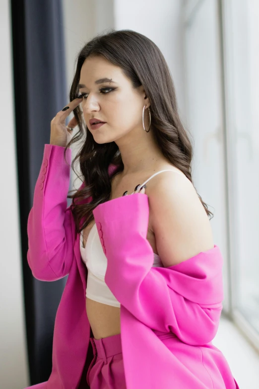 a woman sitting down with a pink coat on