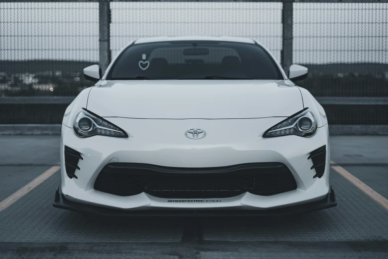 the front end of a white car in a parking lot