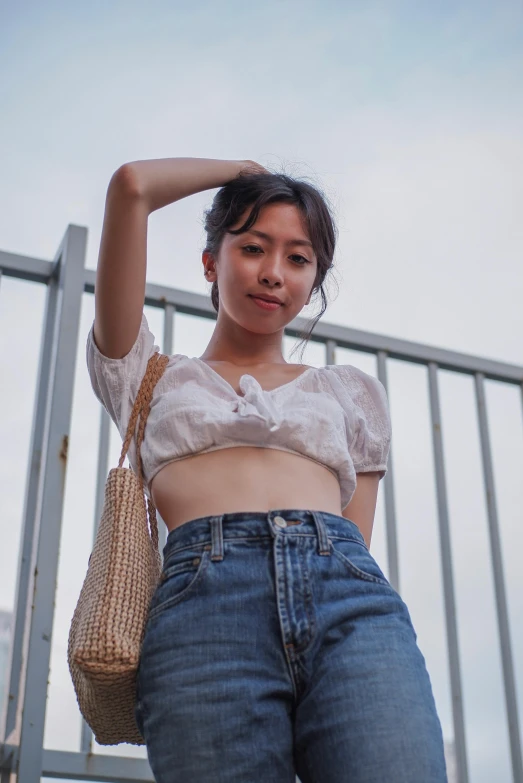 a woman wearing jeans and top next to a metal rail