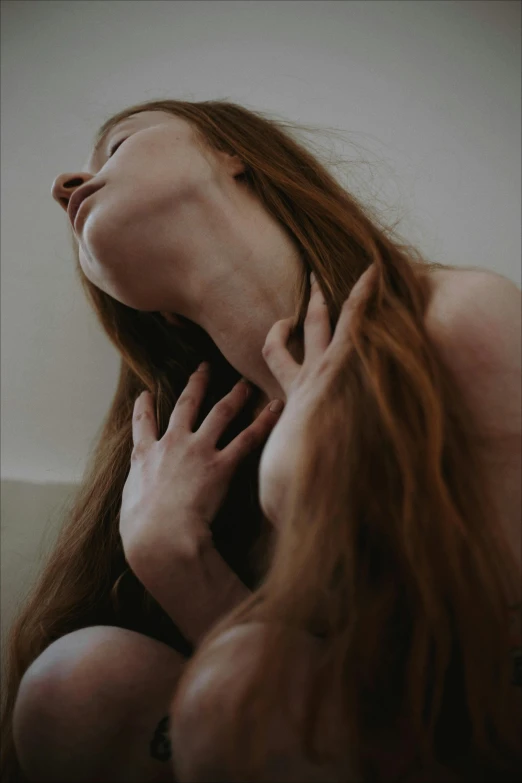 a young woman holds her face in front of her head while she holds her hands close to the neck