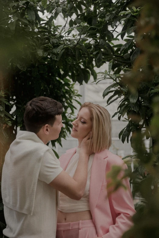 two people standing near each other in front of a tree