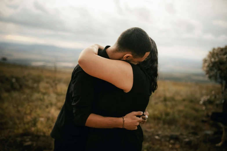 a couple is holding each other in an open field