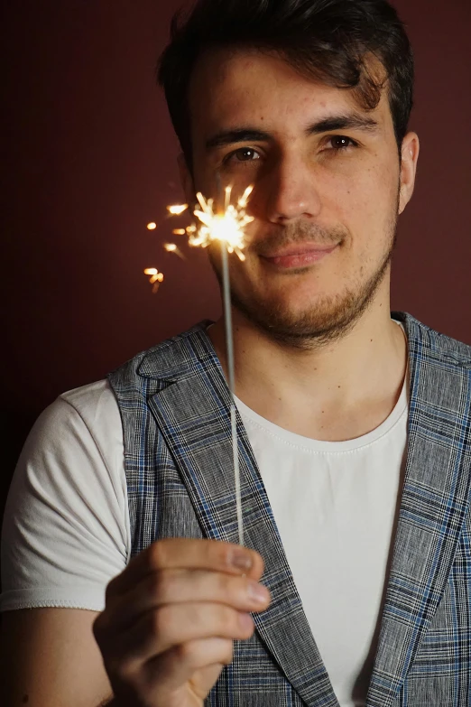 a young man holding up a sparkler