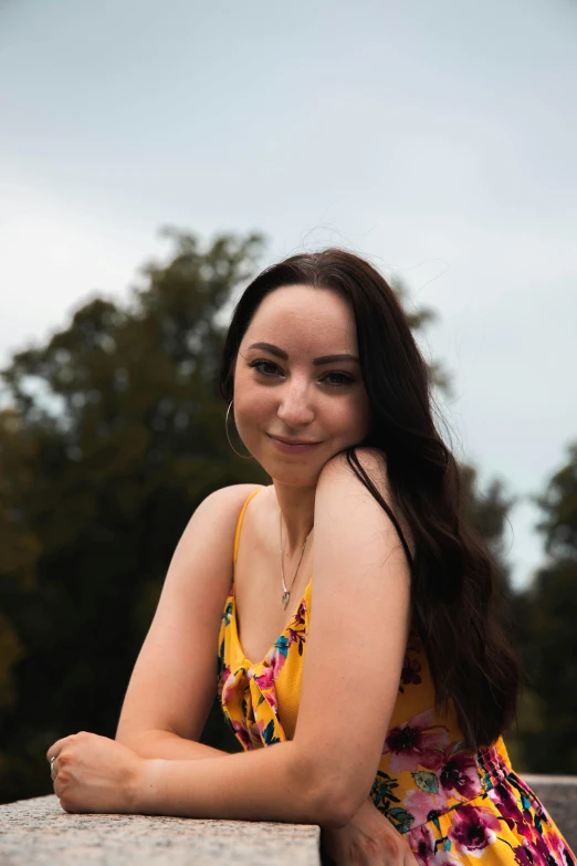 a young woman poses for the camera while sitting on a cement ledge