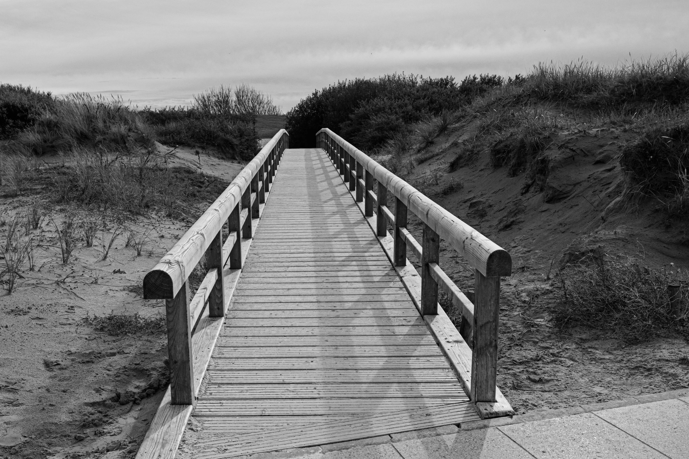 a wooden walkway next to a beach at dusk