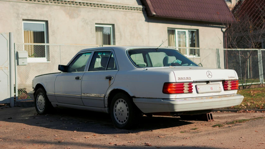 the back of a white car parked outside a building