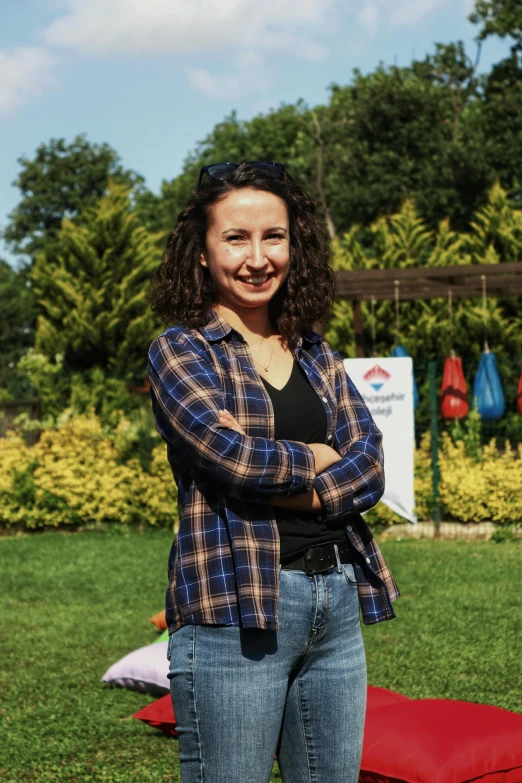 the woman is standing in a field with her arms crossed