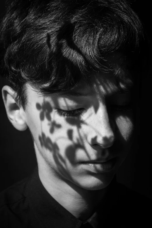 a boy standing in the shade and looking down