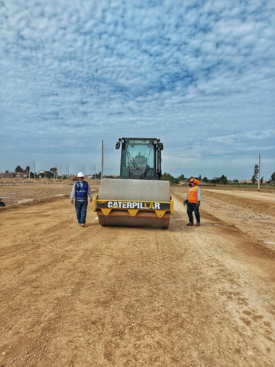 men standing around a bulldozer in the middle of a dirt road