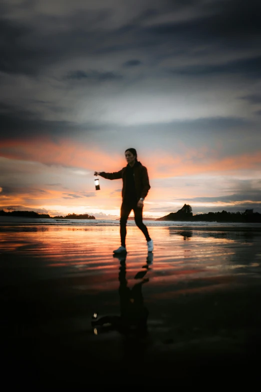 a man is walking along the beach at sunset