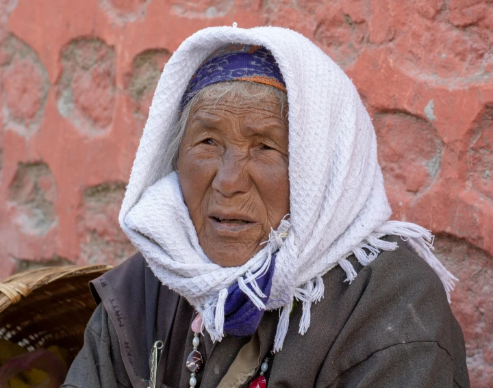 an elderly woman is wearing some linen on her head