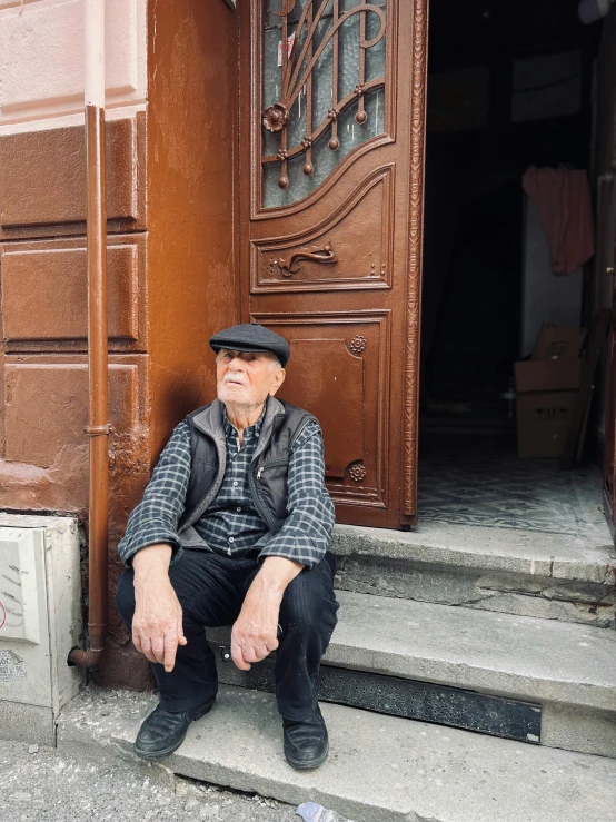 an elderly man sitting on steps at the entrance to a door