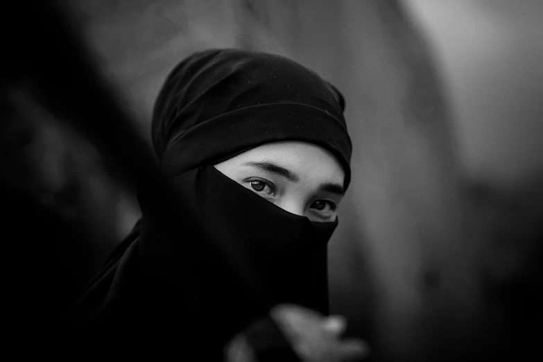 a woman in a black head scarf looking out a window