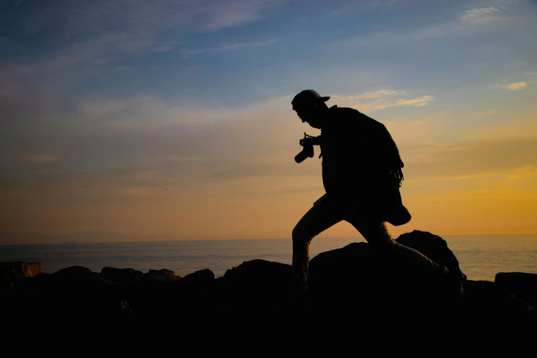 a man is jumping with his cell phone while a sun is setting