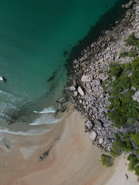 aerial po of boat on sandy ocean and rocks