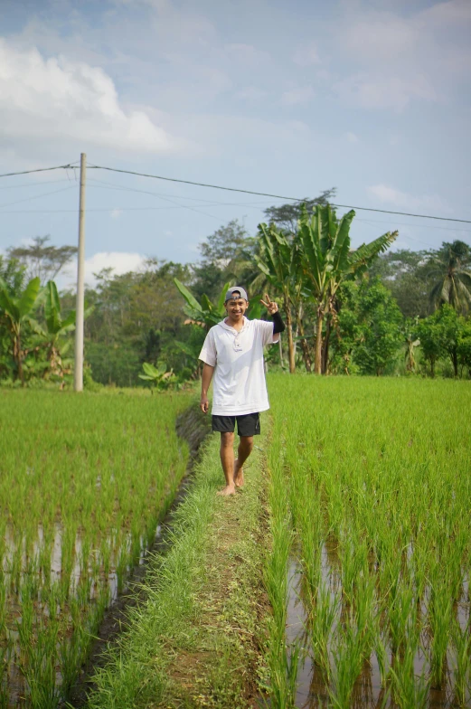 man walking on a dirt path in a large field