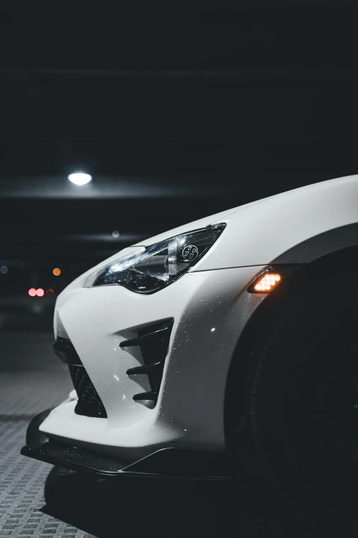 the rear lights and headlights of a white sports car in the dark