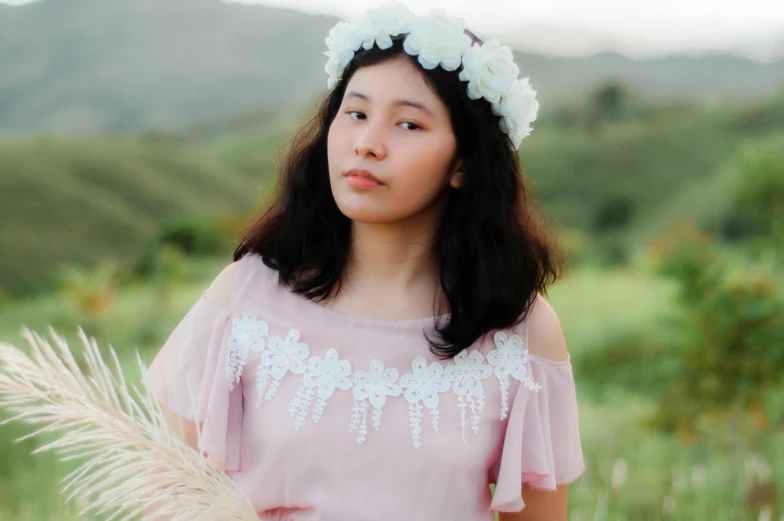 the girl is standing near a bush wearing a flower headband