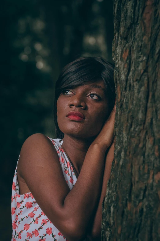 the woman is holding on to the side of a tree