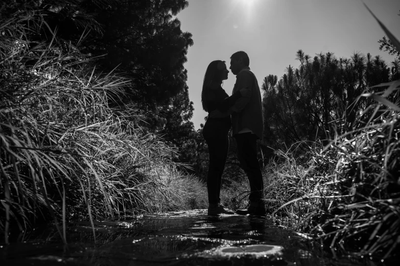 two people in black and white standing near a tree line