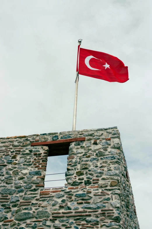 a turkish flag flying from the top of a stone building