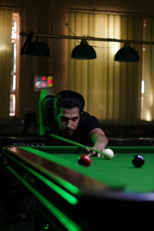 a man leans back while playing pool