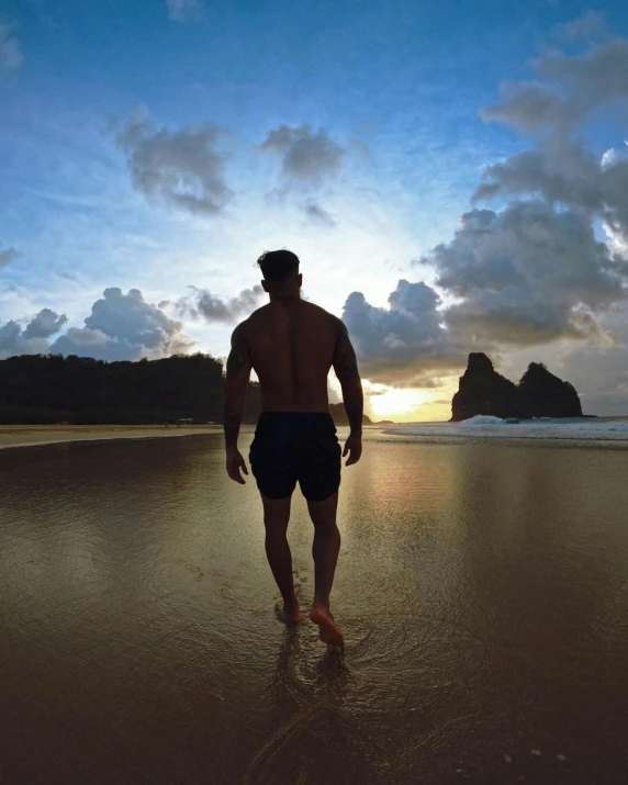 man with  on walking out into the ocean at sunset