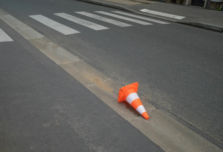 an orange cone is lying in the middle of a street