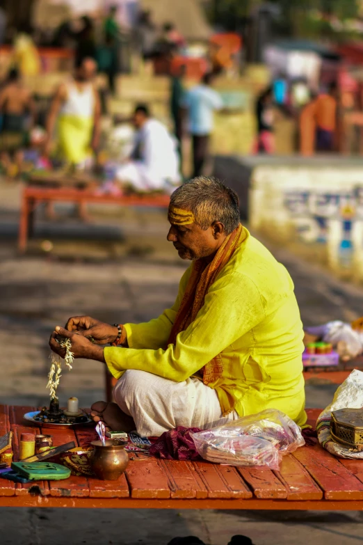 a man sitting on a street bench selling items