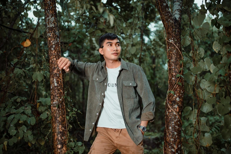 a man standing between trees next to many green leaves