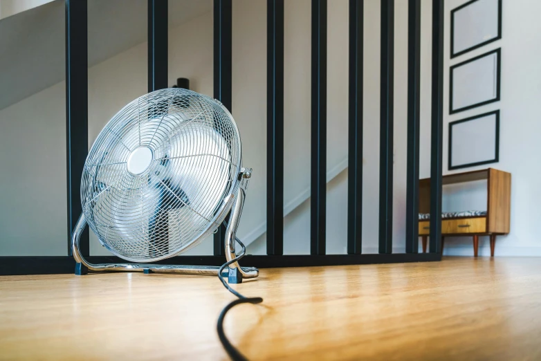 a small silver fan laying on the floor in front of a stair