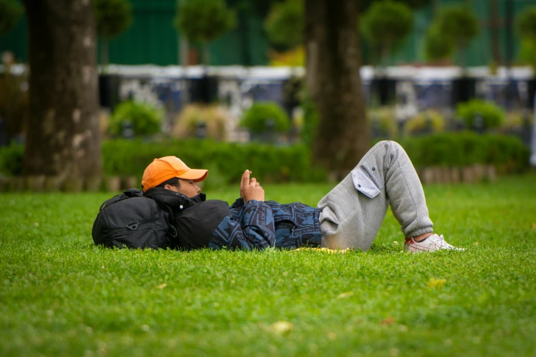 man laying in green grass using his cellphone