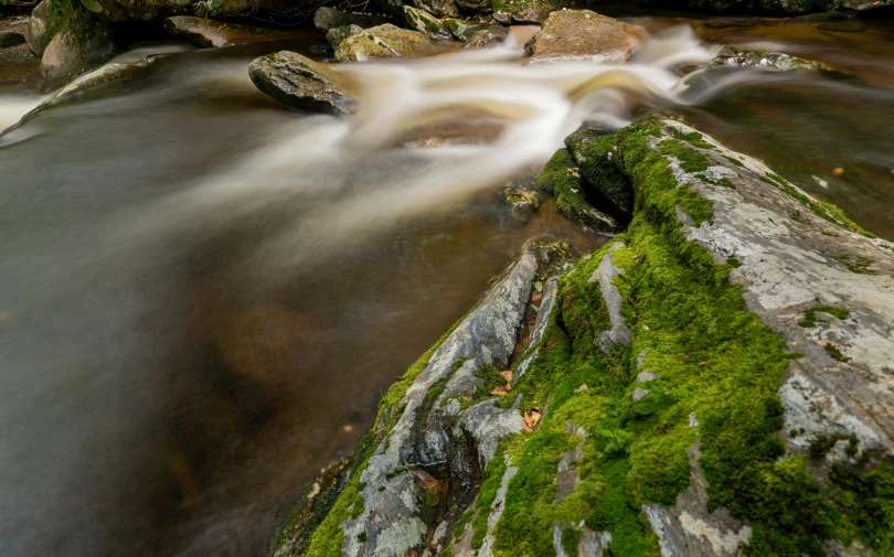 the river flows over rocks in the creek