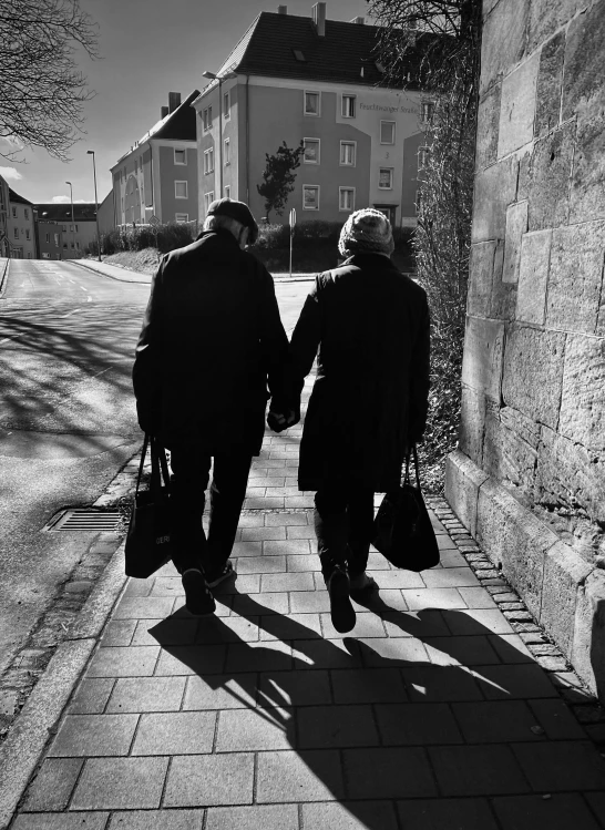 two people walking hand in hand on sidewalk