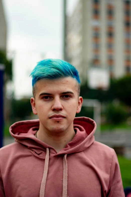 a man with blue hair in a brown and red sweatshirt
