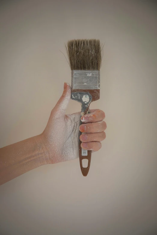 a person holding a paint brush to their right and an empty glove on it